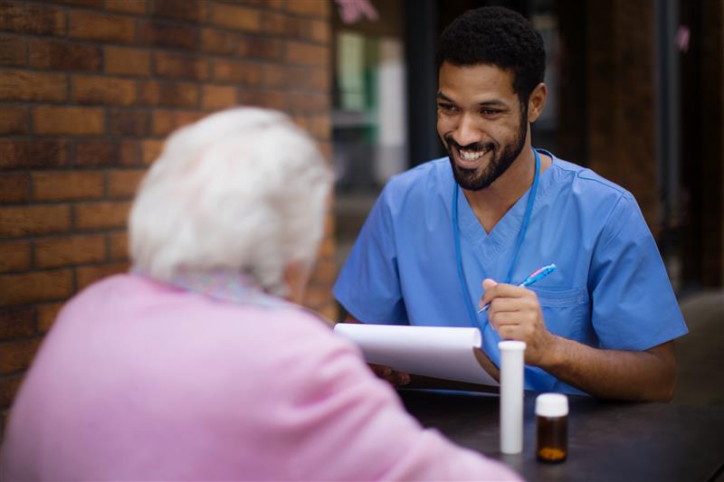 male caregiver taking-pills to senior woman